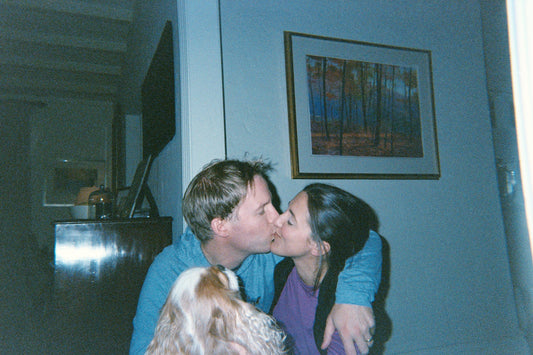 A candid film photo taken by a toddler of their mom and dad kissing