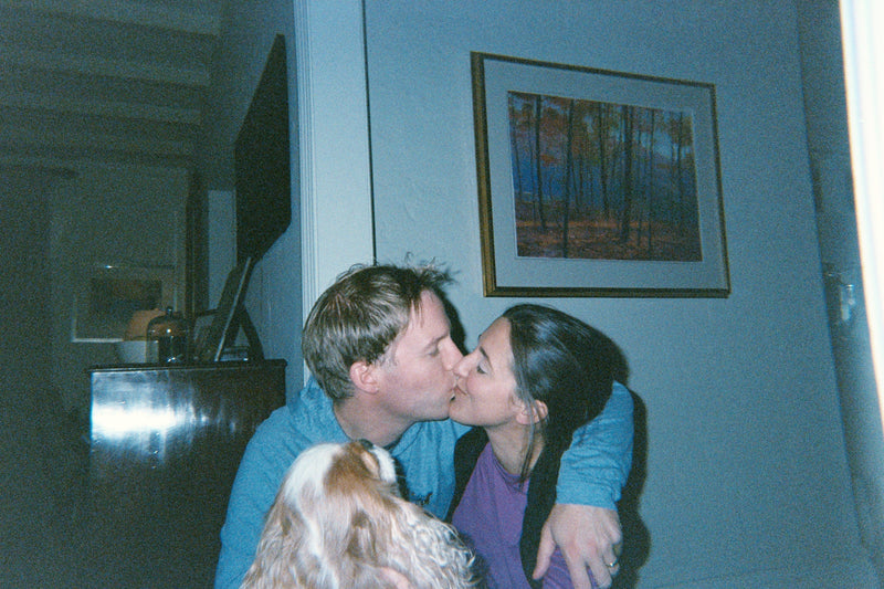A candid film photo taken by a toddler of their mom and dad kissing
